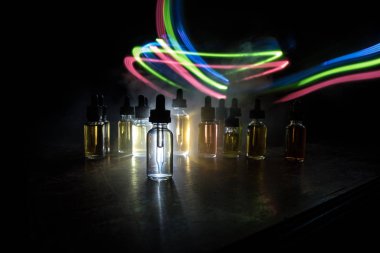 Vape konsepti. Karanlık arka planda duman bulutları ve tüp sıvısı şişeleri. Işık efektleri. Arka plan, vape reklamı ya da vape arkaplan olarak kullanışlı. Seçici odak
