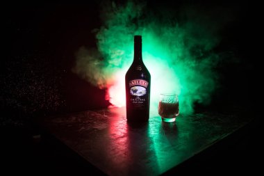 BAKU, AZERBAIJAN - FEB 09, 2020: Baileys Irish Cream is an Irish whiskey- and cream-based liqueur, made by Gilbeys of Ireland. A bottle of liqueur on wooden table with dark toned foggy background.
