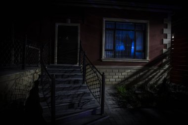 Geceleri hayaletli eski bir ev. Penceredeki korku silueti. Gerçeküstü ışıklar. Korku Cadılar Bayramı konsepti