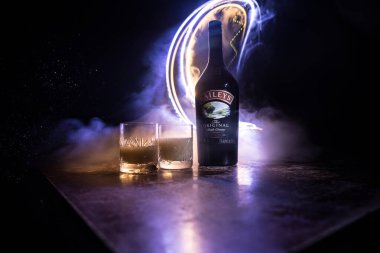 BAKU, AZERBAIJAN - FEB 09, 2020: Baileys Irish Cream is an Irish whiskey- and cream-based liqueur, made by Gilbeys of Ireland. A bottle of liqueur on wooden table with dark toned foggy background.
