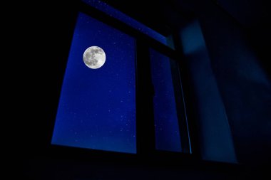 Karanlık odanın penceresinden Ay 'ın gece manzarası görülüyor. Ay ışığı karanlık odada.
