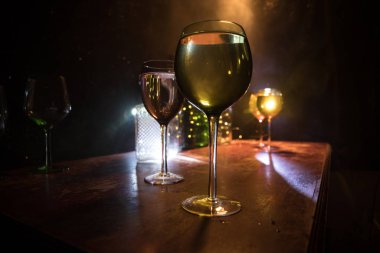 Ahşap masada şarap kadehi ve arka planda güzel renkli ışıklar. Karanlık arka planda şarap kadehleri. Seçici odaklanma. Kulüp içki konsepti