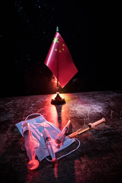 Corona virus concept. china put mask to fight against Corona virus. Concept of fight against virus. China flag and syringes on wooden table