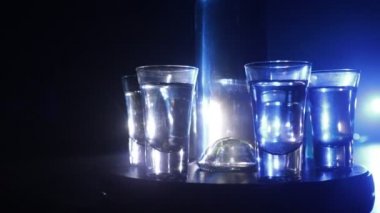 A beautiful carafe with vodka stands on a wooden table with glasses. Dramatic toned foggy background with light. Selective focus. Club drink concept.
