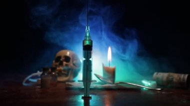 Narcotic drug problem concept. Silhouette of a man standing in the middle of the road on a misty night with giant Drug syringe and narcotic attributes. Creative artwork decoration