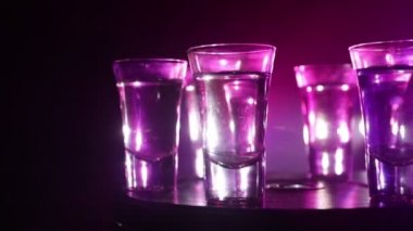 A beautiful carafe with vodka stands on a wooden table with glasses. Dramatic toned foggy background with light. Selective focus. Club drink concept.