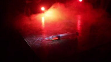 Narcotic drug problem concept. Silhouette of a man standing in the middle of the road on a misty night with giant Drug syringe and narcotic attributes. Creative artwork decoration