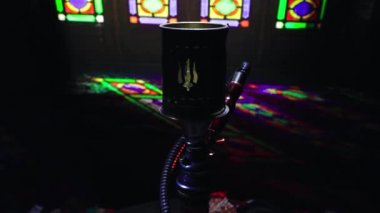 Shisha kasesinde sıcak nargile kömürleri Arap iç kısımlarında buhar bulutları oluşturuyor. Halıdaki doğulu süsü. Karanlıkta arka planda şık bir doğulu shisha..