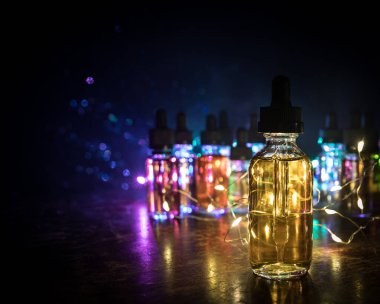 Vape konsepti. Karanlık arka planda duman bulutları ve tüp sıvısı şişeleri. Işık efektleri. Arka plan, vape reklamı ya da vape arkaplan olarak kullanışlı. Seçici odak
