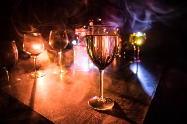 Ahşap masada şarap kadehi ve arka planda güzel renkli ışıklar. Karanlık arka planda şarap kadehleri. Seçici odaklanma. Kulüp içki konsepti