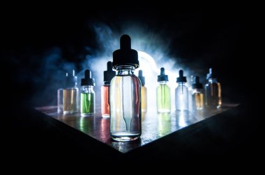 Vape konsepti. Karanlık arka planda duman bulutları ve tüp sıvısı şişeleri. Işık efektleri. Arka plan, vape reklamı ya da vape arkaplan olarak kullanışlı. Seçici odak