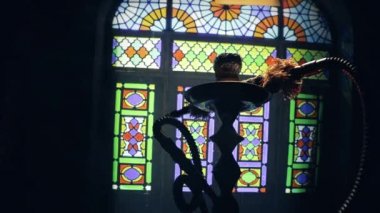 Shisha kasesinde sıcak nargile kömürleri Arap iç kısımlarında buhar bulutları oluşturuyor. Halıdaki doğulu süsü. Karanlıkta arka planda şık bir doğulu shisha..