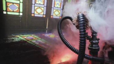 Shisha kasesinde sıcak nargile kömürleri Arap iç kısımlarında buhar bulutları oluşturuyor. Halıdaki doğulu süsü. Karanlıkta arka planda şık bir doğulu shisha..