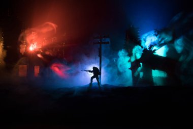 Büyük kalibreli tüfekli ordu keskin nişancısı ateş ve dumanın içinde duruyor. Savaş Konsepti. Savaş sahnesi sisli gökyüzü arka planında geceleri Bulutlu Skyline 'ın altında siluetlerle savaşmak. Şehir savaş yüzünden yok oldu.