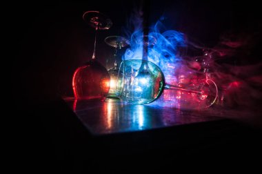 Boş şarap kadehini ahşap masaya koy ve arka planda güzel renkte ışıklar olsun. Karanlık arka planda şarap kadehleri. Seçici odaklanma. Kulüp içki konsepti