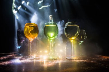 Ahşap masada şarap kadehi ve arka planda güzel renkli ışıklar. Karanlık arka planda şarap kadehleri. Seçici odaklanma. Kulüp içki konsepti