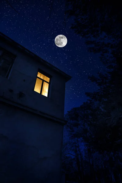 Beautiful landscape of building at forest at night with moon and stars. Scary abandoned house at night with ghost. Cold autumn night