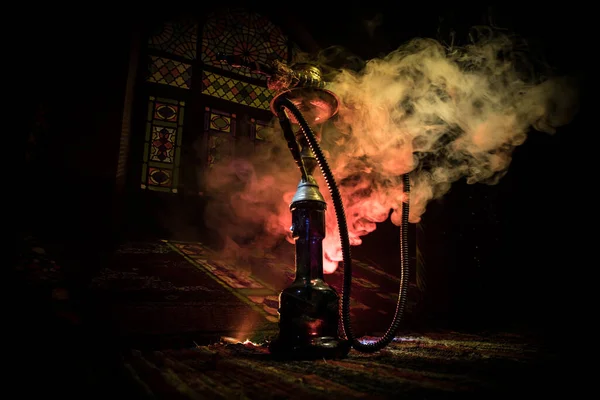 胡卡炽热的煤块在什沙碗上 在阿拉伯内部形成蒸汽云 地毯上的东方饰物 色彩艳丽的东方沙司在黑暗中背光 — 图库照片