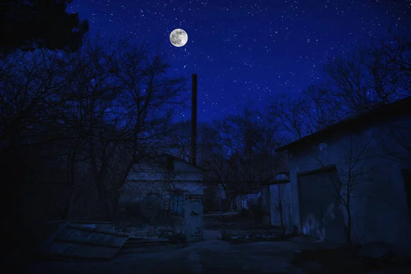Beautiful landscape of building at forest at night with moon and stars. Scary abandoned house at night with ghost. Cold autumn night