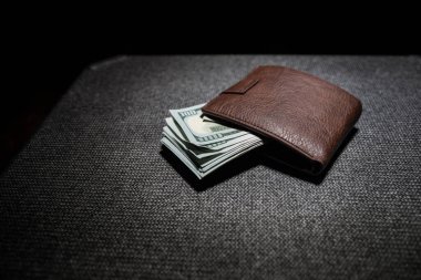 Ahşap arka planda parası olan şık bir erkek çantası. Para, kredi ve banka kartlarıyla dolu bir erkek cüzdanı.