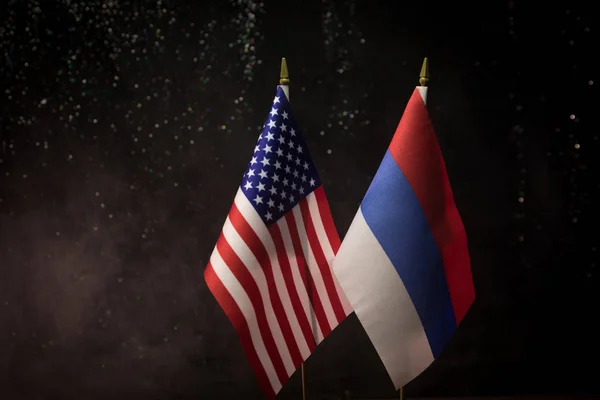 Russia and USA small flag on dark background. Concept of crisis of war and political conflicts between nations. Selective focus