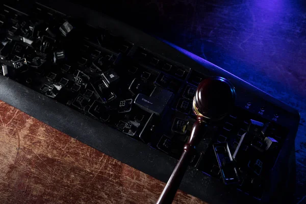 Broken keyboard with mallet of justice on wooden table. Keyboard destroyed with mallet of justice.