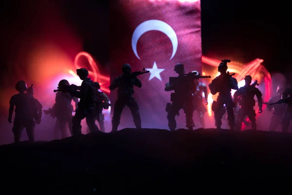 Turkish army concept. Silhouette of armed soldiers against a Turkish flag. Creative artwork decoration. Military silhouettes fighting scene dark toned foggy background. Selective focus