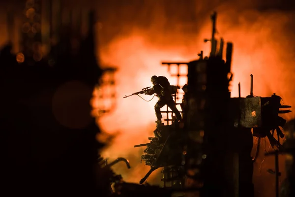 大口径步枪的陆军狙击手站在火堆和烟雾中 战争概念 战争雾天背景下的战斗场景 夜晚在云天线下的战斗轮廓 被战争摧毁的城市 — 图库照片