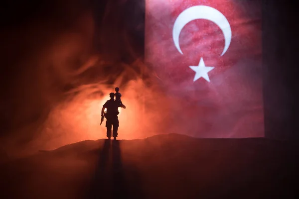 Turkish army concept. Silhouette of soldiers against a Turkish flag. Creative artwork decoration. Turkish soldier carrying little boy on his shoulder. Selective focus