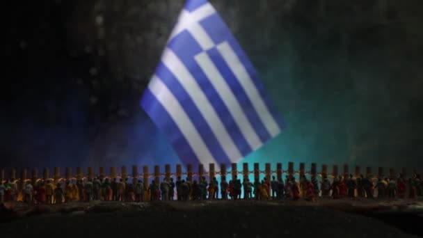 Nahaufnahme Einer Griechischen Flagge Mit Überfüllten Flüchtlingsfiguren Auf Dunklem Hintergrund — Stockvideo