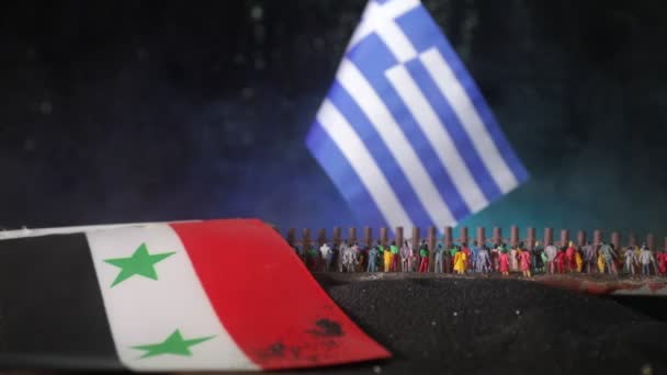 希腊国旗的特写镜头 在黑暗背景下 地面上有拥挤的难民和叙利亚国旗 — 图库视频影像