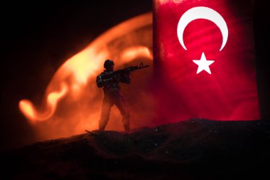 Türk ordusu konsepti. Türk bayrağına karşı silahlı asker silueti. Yaratıcı sanat dekorasyonu. Askeri siluetler dövüş sahnesinde sisli bir arka planda. Seçici odak