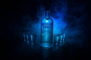 BAKU, AZERBAIJAN - FEB 09, 2020: Absolut Vodka is a brand of vodka, produced near Ahus, in Sweden. Owned by French group Pernod Ricard. Bottle of vodka on wooden table with dark toned foggy background.