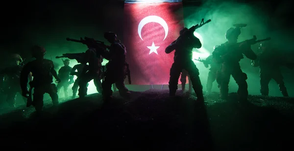 Turkish army concept. Silhouette of armed soldiers against a Turkish flag. Creative artwork decoration. Military silhouettes fighting scene dark toned foggy background. Selective focus