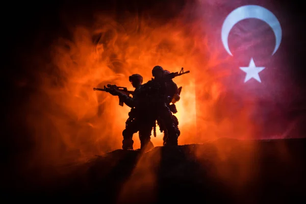 Turkish army concept. Silhouette of armed soldiers against a Turkish flag. Creative artwork decoration. Military silhouettes fighting scene dark toned foggy background. Selective focus