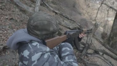 Maskeli ve tüfekli bir adam ormana saldırmaya hazır. Silah doğrultan tehlikeli bir haydut. Dağ yolundaki askeri harekat sırasında özel asker..