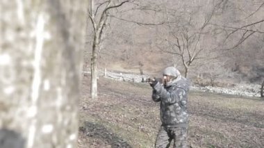 Maskeli ve tüfekli bir adam ormana saldırmaya hazır. Silah doğrultan tehlikeli bir haydut. Dağ yolundaki askeri harekat sırasında özel asker..