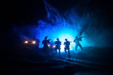 Savaş Konsepti. Savaş sahnesi sisli gökyüzü arka planında geceleri Bulutlu Skyline 'ın altında siluetlerle savaşmak. Askerlerin sanat eserleriyle donatılmış askeri araç. Seçici odak