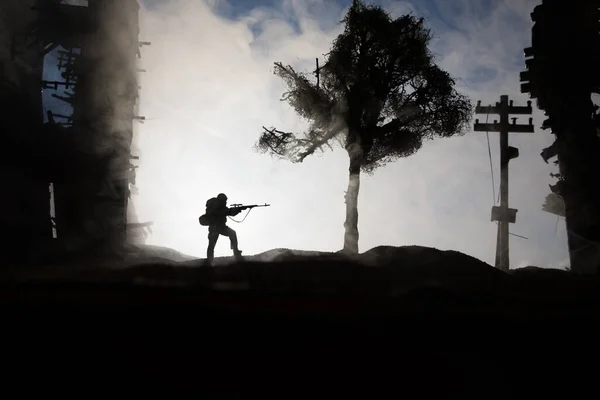 Army sniper with large caliber rifle standing in the fire and smoke. War Concept. Battle scene on war fog sky background, Fighting silhouettes Below Cloudy Skyline at sunset. City destroyed by war