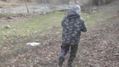 Maskeli ve tüfekli bir adam ormana saldırmaya hazır. Silah doğrultan tehlikeli bir haydut. Dağ yolundaki askeri harekat sırasında özel asker..