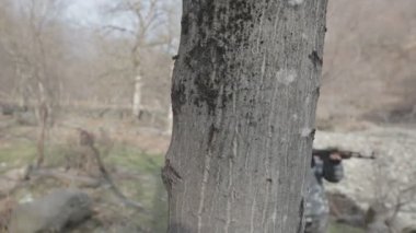 Maskeli ve tüfekli bir adam ormana saldırmaya hazır. Silah doğrultan tehlikeli bir haydut. Dağ yolundaki askeri harekat sırasında özel asker..