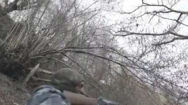 Maskeli ve tüfekli bir adam ormana saldırmaya hazır. Silah doğrultan tehlikeli bir haydut. Dağ yolundaki askeri harekat sırasında özel asker..