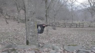 Maskeli ve tüfekli bir adam ormana saldırmaya hazır. Silah doğrultan tehlikeli bir haydut. Dağ yolundaki askeri harekat sırasında özel asker..