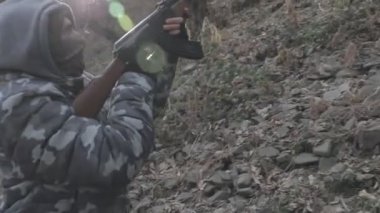 Maskeli ve tüfekli bir adam ormana saldırmaya hazır. Silah doğrultan tehlikeli bir haydut. Dağ yolundaki askeri harekat sırasında özel asker..