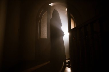 Kapalı cam bir kapıdan geçen, bilinmeyen bir gölge figürünün silueti. Geceleri arka planda duman olan ürkütücü siluet kız.