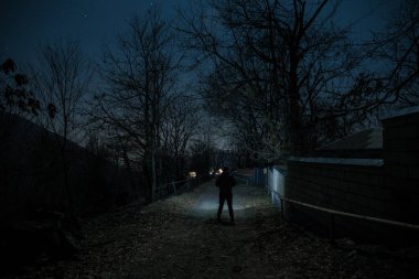 Gece sessiz köyde dolunay var. Ay ışığı altındaki dağ köyünün güzel gece manzarası. Karanlıkta duran bir insan silueti. Seçici odaklanma. Uzun pozlu çekim
