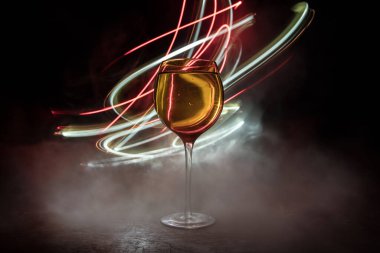 Ahşap masada şarap kadehi ve arka planda güzel renkli ışıklar. Karanlık arka planda şarap kadehleri. Seçici odaklanma. Kulüp içki konsepti