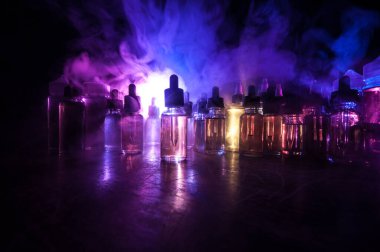 Vape konsepti. Karanlık arka planda duman bulutları ve tüp sıvısı şişeleri. Işık efektleri. Arka plan, vape reklamı ya da vape arkaplan olarak kullanışlı. Seçici odak