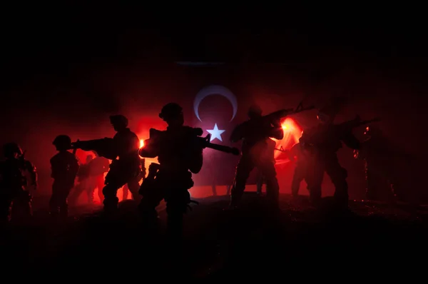 Turkish army concept. Silhouette of armed soldiers against a Turkish flag. Creative artwork decoration. Military silhouettes fighting scene dark toned foggy background. Selective focus