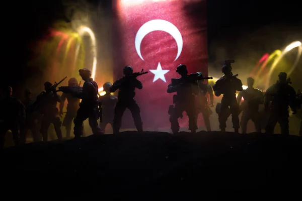 Turkish army concept. Silhouette of armed soldiers against a Turkish flag. Creative artwork decoration. Military silhouettes fighting scene dark toned foggy background. Selective focus